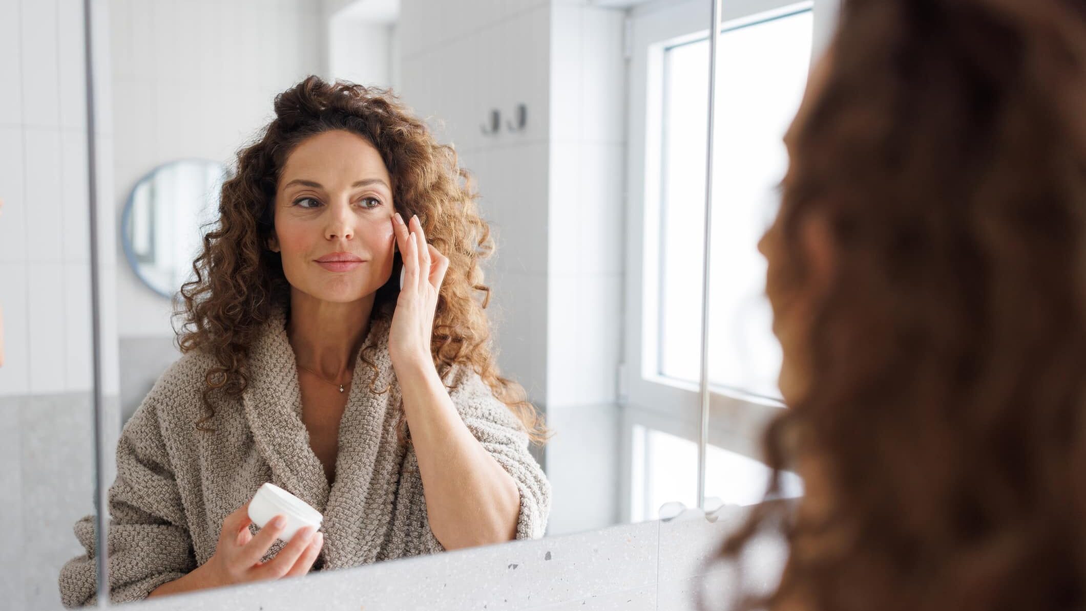 Mid adult woman applying skincare cream in the bathroom